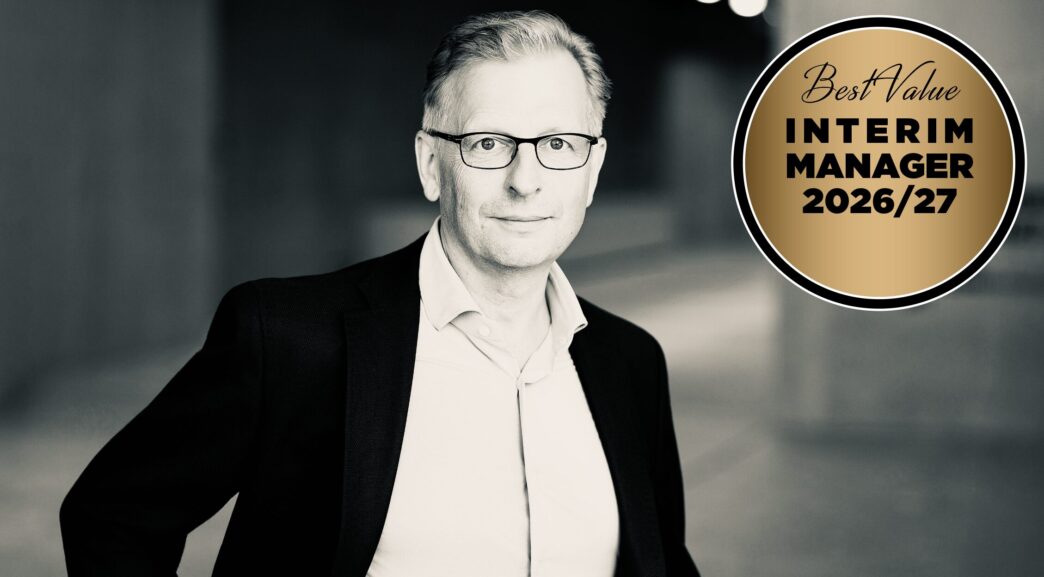 Black-and-white portrait of a man in a suit and glasses next to a gold circular badge that reads 'Best Value Interim Manager 2026/27'.