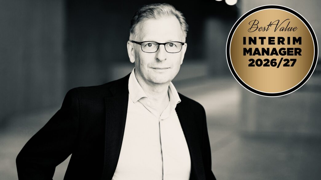 Black-and-white portrait of a man in a suit and glasses next to a gold circular badge that reads 'Best Value Interim Manager 2026/27'.