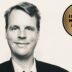 Black-and-white portrait of a smiling man in a suit with a gold circular badge reading 'Best Value Interim Manager 2026/27' on the right.