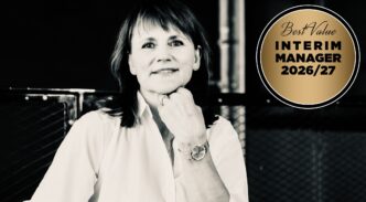Black-and-white portrait of a smiling woman with her hand on her chin, next to a gold circular badge reading ‘Best Value Interim Manager 2026/27’.